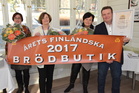 Oikealla kauppiaspariskunta Kim ja Carita Mattsson, vasemmalla leipäosaston hoitajat Armi Vähäsarja ja Tuula Heino. Banderolli ripustetaan kaupassa leipäosaston yläpuolelle.